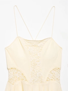Detail of light yellow dress with spaghetti straps and white floral lace inserts