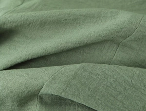 Detailed close-up of sage green textured fabric with fine stitching and woven grain