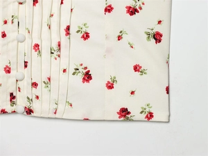 Detail of floral backless top featuring side pleats and three white button accents