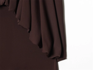 Detailed view of layered drapes and ruffles on a dark brown slim fit dress fabric