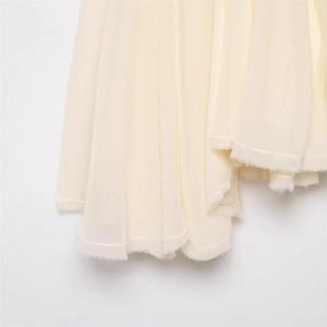 Close-up of cream chiffon dress hem featuring soft raw edge details and textured fabric