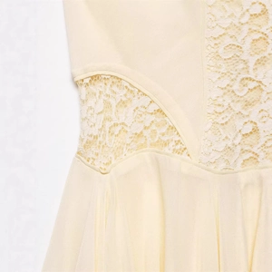 Close-up of delicate beige lace floral embroidery and chiffon fabric on dress