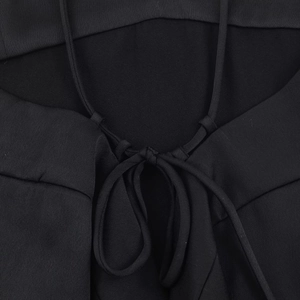 Detailed close-up of the delicate lace-up back bow on a black satin camisole top