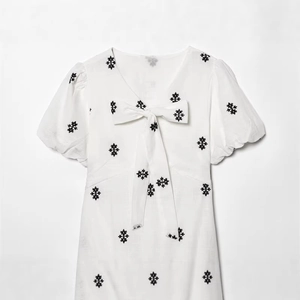 White puff sleeve dress with black star embroidery and large bow neckline detail