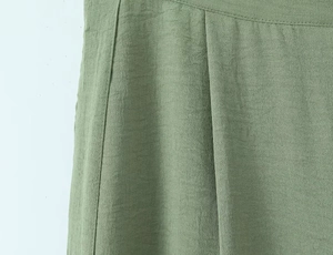 Detailed macro view of pea green cotton linen fabric with waist pleats and stitching