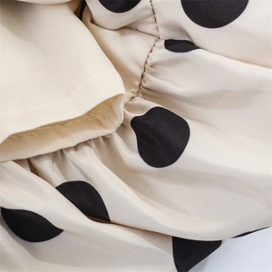 Detailed close-up of polka dot fabric texture with ruffles and fine stitching