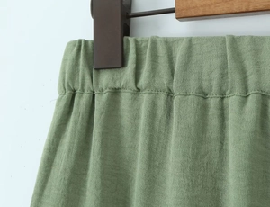 Detailed macro view of the elastic waistband on light green linen blend trousers