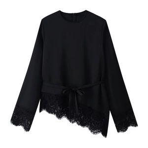 Detail of elegant black long-sleeve top with delicate lace trim and belted waist bow