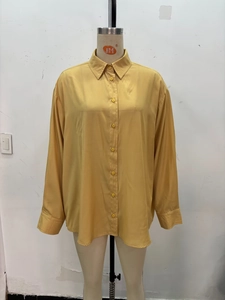 Détail d'une chemise en soie jaune moutarde avec col polo et boutons assortis