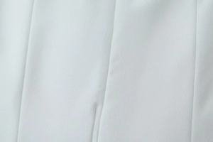 Gros plan sur le tissu tissé blanc montrant les coutures et la texture lisse du vêtement