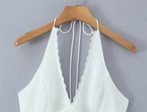 Detailed view of white lace halter top featuring floral embroidery and V-neckline