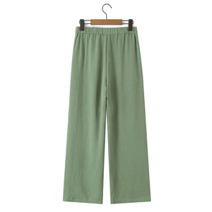 Detail of light green wide-leg trousers with elastic waistband and crinkle texture fabric