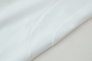 Gros plan sur les coutures précises et la texture du tissu blanc de cette robe longue