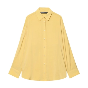 Détail du chemisier jaune clair à boutonnage simple et avec une finition d'ourlet arrondi