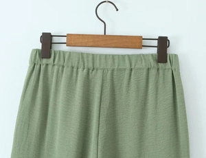 Detail of light green cotton linen trousers with elastic waist and textured fabric
