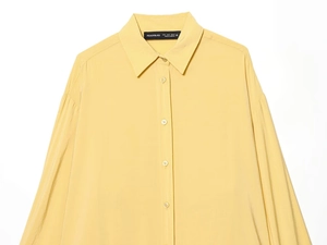Détail d'une chemise boutonnée jaune pâle avec col pointu et tissu à texture légère