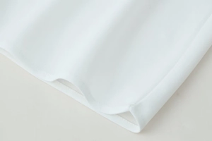Détail de l'ourlet de robe en mousseline blanche avec couture fine et fente latérale