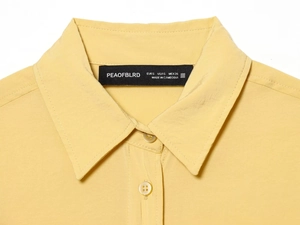 Gros plan du col polo et de l'étiquette de marque sur une chemise jaune clair