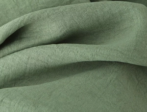 Detailed macro view of pea green textured fabric with natural fiber weave and soft drapes