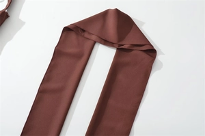 Detail of dark brown chiffon waist strap with fine stitching and smooth matte texture