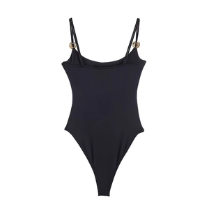 Detail of black bodysuit with thin straps and decorative gold metal rings on plain background