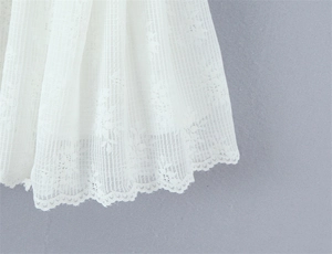 Detail of white mesh fabric featuring intricate floral lace and scalloped edge finish