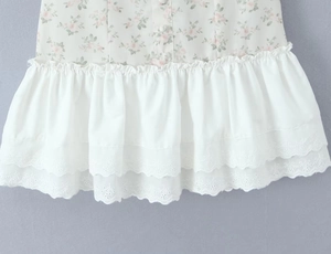 Detail of floral print fabric with eyelet embroidery hem and white fabric buttons