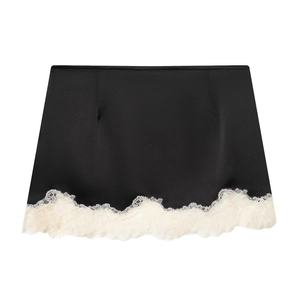 Détail de l'ourlet de la jupe en satin noir avec une bordure en dentelle blanche