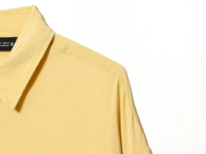 Détail du col polo et des coutures de cette chemise jaune à manches courtes pour femme