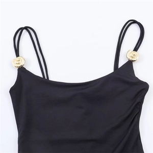 Detail of black bodysuit featuring double thin straps and golden shell metal accents