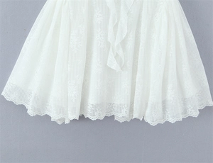 Detailed view of white floral lace fabric with scalloped edges on a spring dress