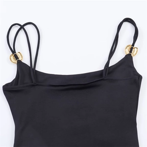 Detail of black bodysuit featuring thin double straps and gold wavy metal rings