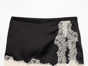 Détail d'une mini-jupe en satin noir montrant la bordure en dentelle et le zip invisible