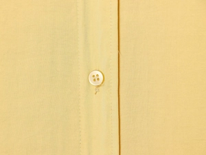 Détail rapproché du tissu jaune texturé et de la fermeture à boutons soignée