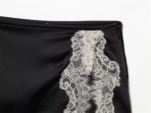 Détail du tissu en satin noir avec bordure en dentelle blanche et fermeture éclair invisible
