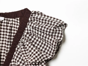 Detail von braunem Gingham-Stoff mit elastischem Smok-Saum und plissierten Rüschenärmeln