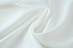 Detailed view of soft white satin fabric texture with elegant silky folds and smooth sheen