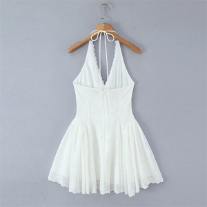 Detailed view of white lace halter dress with deep V-neck and delicate floral embroidery