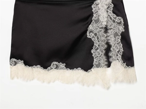 Détails de la jupe en satin noir avec bordure en dentelle blanche sur l'ourlet et la fente