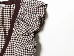 Detailansicht des Oberteils mit Gingham-Muster, Seersucker-Stoff und Rüschenmanschetten