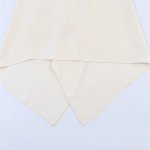 Detail of the asymmetric handkerchief hem design and precise stitching on the beige top