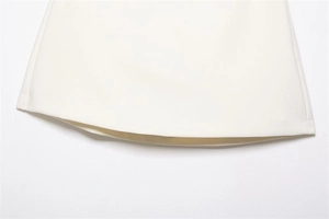 Detail view of the white woven fabric texture and high-quality hem stitching on the skirt