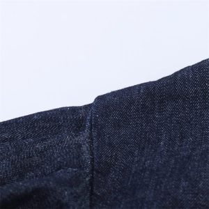 Gros plan des doubles coutures et de la texture sergée de la robe en jean bleu foncé