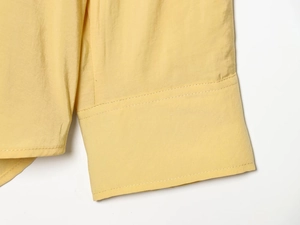 Gros plan du poignet de chemise jaune avec double couture précise et texture de tissu premium