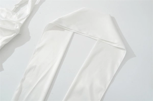 Detail of the white satin fabric showing soft silk texture and neat edge stitching