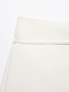 Detailed close-up of white pleated culottes showing high-quality fabric and belt loops