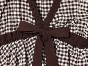 Detail von braunem Gingham-Seersucker-Stoff mit Rüschen-V-Ausschnitt und Schleife