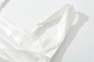 Detail of adjustable silver buckles on white satin dress straps with silk texture
