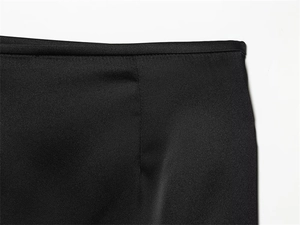 Vue détaillée de la texture du satin noir et des coutures précises à la taille de la jupe