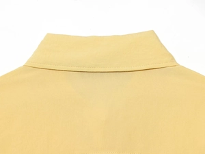Détail rapproché du col polo et des coutures sur une chemise d'été jaune clair